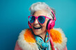 © happy_finch - Happy elderly lady in sunglasses laughs while listening to music on blue background