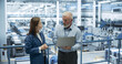 © Gorodenkoff - Industrial Engineers Working at a Technology Factory. Caucasian Man and Japanese Female Using Laptop Computer and Having a Conversation. Portrait of a Couple at Work