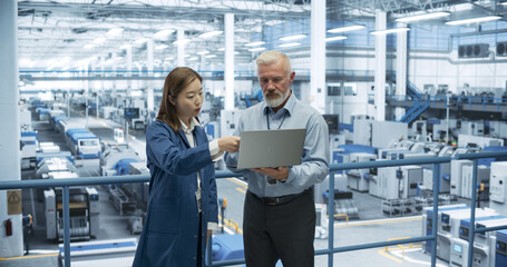 Poster - Male Engineer and Female Project Manager Standing on a Platform, Talking, Using Laptop Computer and Monitoring Production at a Modern Automated Electronics Manufacture with AI Robots