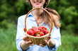 Smiling young woman holds a basket with ripe strawberries in her hands. Harvest strawberries. Close-up.