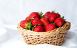 Ripe juicy strawberries in a wicker basket on a white background. Close-up. Selective focus.