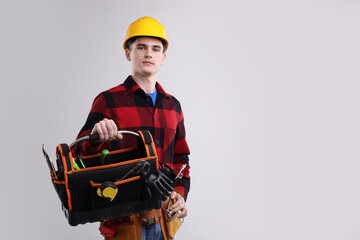 Canvas Print - Professional repairman with tool box on light grey background. Space for text