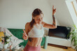 © Daria - A woman is joyfully dancing in a living room with her arms raised in the air