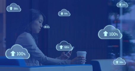 Poster - Image of cloud symbols uploading data over asian businesswoman using smartphone at cafe