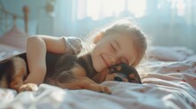 A Little Girl Tenderly Hugs Her Puppy And Lies On The Bed In A Bright Bedroom In The Morning. Friendship Concept Between Child And Pet, Copy Space For Text
