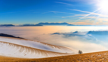 Sunny foothills and hills and a Plain with Fog with Mountain Range on Background against a clear blue sky with clouds and copy space. Winter landscape with snow. Generative Ai.