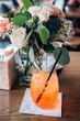Bright orange Aperol Spritz cocktail amid pretty floral arrangement