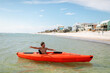 Boy in kayak by beach homes on a sunny day