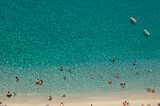 Fototapeta Na ścianę - Aerial view of sandy beach with swimming people in sea with transparent blue water in summer.