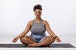 Biracial young female plus size model practices yoga on white background, copy space