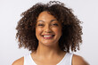 A biracial young plus size model smiles, wearing white tank top