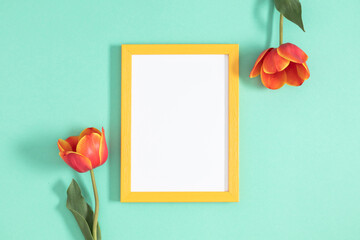 Wall Mural - festive floral background. beautiful tulip flowers and yellow empty photo frame on a pastel mint bac
