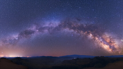 A mesmerizing panorama of the Milky Way galaxy unfolding above a serene desert mountain range at night.
