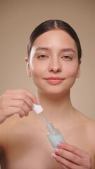 Wall Mural - young beautiful woman applying face serum with pipette on her face close up. cosmetic procedures for