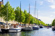 Scenic view Christianshavn Copenhagen canal marina embankment with many boats vessel yachts moored against green trees and blue sky on sunny day. Christianshavn harbor neighborhood district cityscape