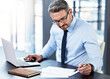 © peopleimages.com - Laptop, paper and businessman with thinking in office for investment, portfolio review and update. Professional person, mature broker and tech with documents for stock market, analysis and planning