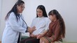 Happy pregnant asian woman appointment with doctor while daughter by side at hospital or clinic, doctor using stethoscope listening baby heartbeat for diagnose health, pregnancy and medical.