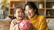 © AIGen - happy mother and daughter holding a pink piggy bank on a sofa, generative ai