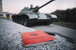 Military ID of the Russia on a stone on background of a tank. Mobilization in Russia . Russian inscription on the document Military ID of the Russian Federation.