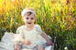 Happy little girl sitting in a flower field on a sunny day