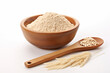 a wooden bowl of brown rice flour and 1 spoon of brown rice grains on a white background