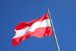 Austrian flag with red stripes and white stripe waving in the blue sky of the capital Vienna