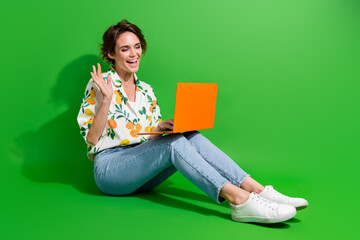 Canvas Print - Full body photo of student girl greetings on video conference with her parents waving palm to notebook isolated over green color background