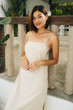 Attractive asian woman in a beige dress is standing outdoors