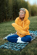 cute girl with glasses in an orange hoodie is sitting in a park in nature expressing kind emotions