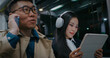 People traveling in metro, train or bus. Man with glasses and raincoat talking on mobile phone. Girl wearing white headphones over long dark hair. Enjoying music. Holding tablet device with both hands