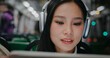 Portrait of Chinese girls face. Beautiful woman wearing new white headphones. Using large tablet device or laptop. Actively glancing at big screen of digital device. Finding ways of entertainment.