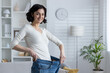 © Tetiana - Smiling woman showcasing weight loss by holding large jeans