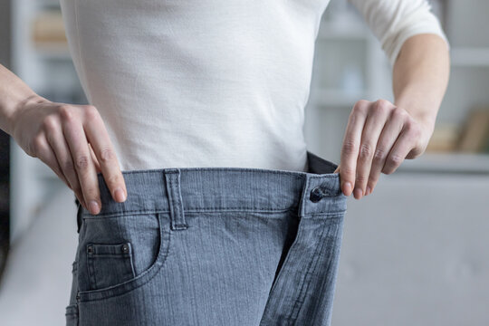 young woman showing weight loss by fitting into old jeans