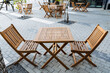Outdoor furniture set with wooden table and chairs on a brick sidewalk