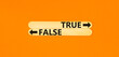 True or false symbol. Concept word True or False on beautiful wooden stick. Beautiful orange table orange background. Business and true or false concept. Copy space.