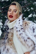 Beautiful young woman with perfect skin. A woman in a lynx fur coat against the backdrop of a snowy forest. Luxurious furs, expensive luxury clothes. Clothes advertising. Skin care cosmetics.