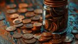   A jar filled with coins sits on a wooden table next to a pile of one hundred pennies