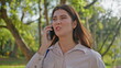 Annoyed woman talking cellphone looking frustrated walking green park closeup. 