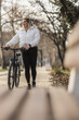 Woman Walking Bike In City Park