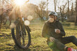 Man Sitting Next to Bike in a Park
