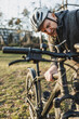 Senior Cyclist Inspects His Mountain Bike in a Park