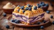   A tight shot of a cake slice on a plate, adorned with blueberries atop and whipped cream drizzled over