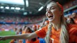 A female fan is smiling and enjoying the soccer game at the stadium