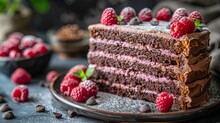   A Slice Of Chocolate Cake, Adorned With Raspberries And Chocolate Chips, Sits On A Plate Nearby, A Bowl Brims With Fresh Raspberries