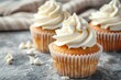 Three delicious cupcakes with white frosting on a table. Perfect for bakery or dessert concepts