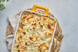 A cheesy macaroni and cheese cauliflower casserole in a yellow handled dish