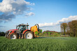 Getreideanbau - roter Traktor mit angebauter Feldspritze bei einer Pflanzenschutzmaßnahme im Getreidefeld.