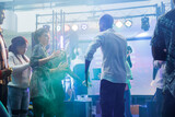 Fototapeta Tulipany - Man and woman friends showing fun moves at dance battle while partying in nightclub. Dancers improvising on dancefloor illuminated with colorful lights while celebrating in club