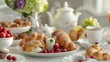Arrange a continental breakfast on an elegant table setting. Include croissants, pastries, fresh fruits, yogurt, and a pot of coffee or tea