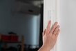 Hand gently touches the Jewish mezuzah on the doorpost, a prayer for home protection in Judaism. White interior, stylish modern mezuzah in Israel.